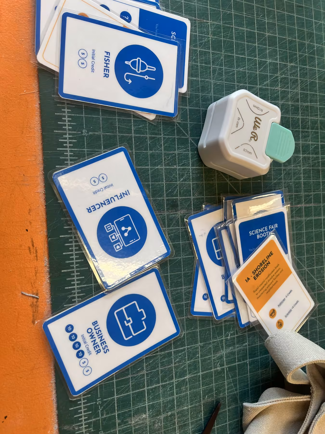 Role and event cards on a cutting mat during assembly